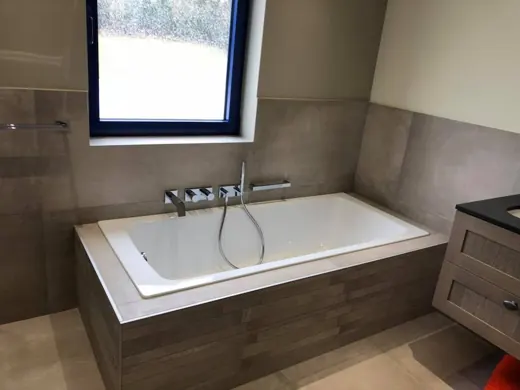 Baignoire encastrée dans un habillage carrelé avec robinetterie murale