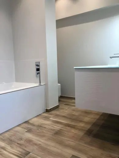 Salle de bain avec baignoire encastrée et sol effet bois